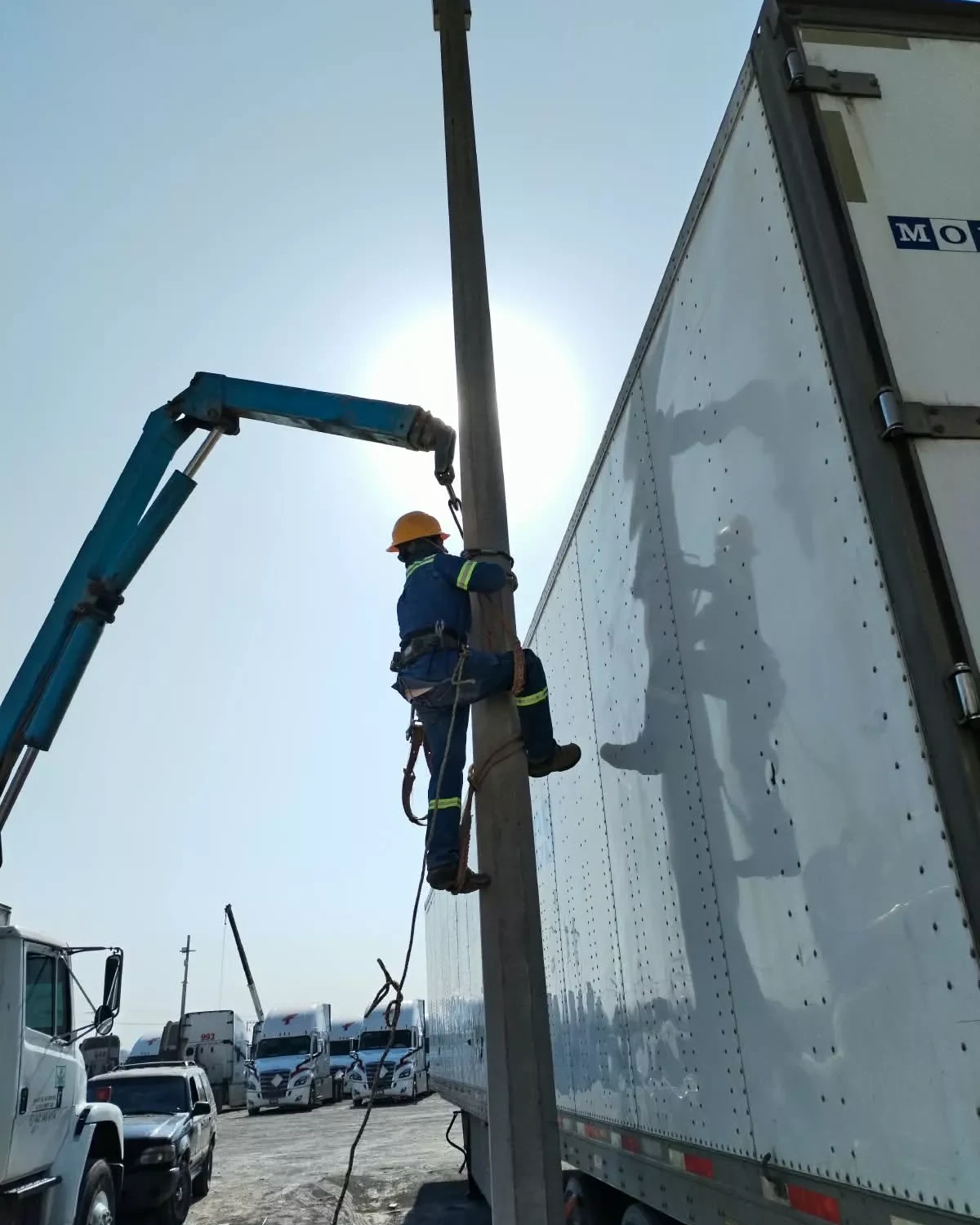 Técnico con arnés instalando un poste con apoyo de una grúa