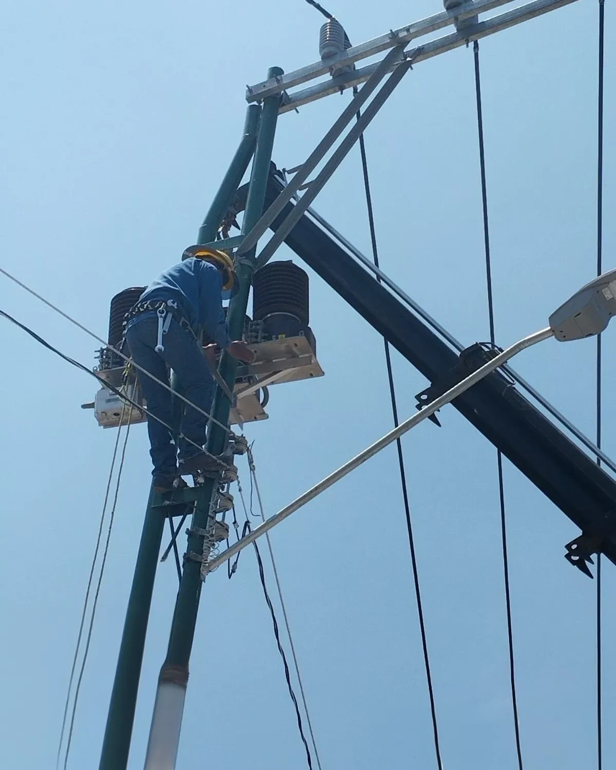 Técnico realizando trabajos en un poste de media tensión como parte de un proyecto eléctrico