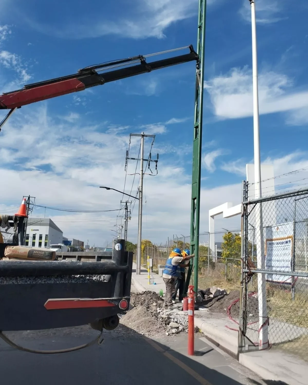 Grúa instalando un poste de media tensión en una instalación industrial